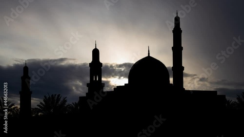 Muscat, Oman: Al Qubrah Mosque at Sunrise, Time Lapse with Fast Clouds and Dark Silhouette of Minarets and Dome photo
