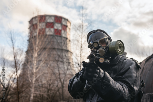 Post apocalypse soldier with a rifle and in the gas mask on the factory chimney background.