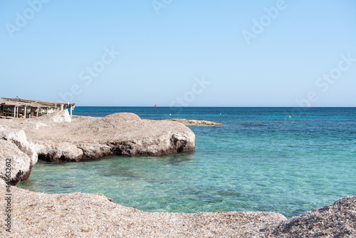 Rocky side of Migjorn beach on a sunny day in Formentera, Spain photo