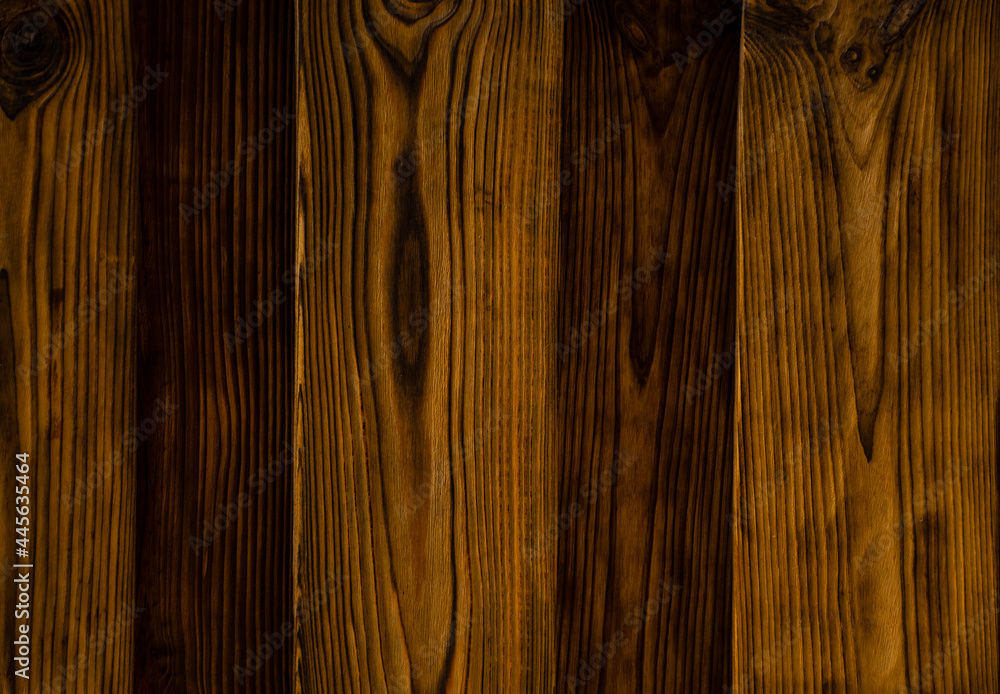 Obraz premium Background of an old natural wooden darken embossed fence of beech texture inside vintage, retro proper vertical warm rural interior with wood, shadows,