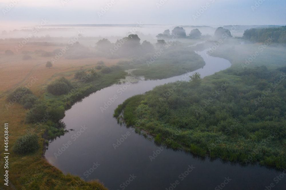 Aerial view of winding river. Misty sunrise above the meadow. Beautiful landscape of nature.