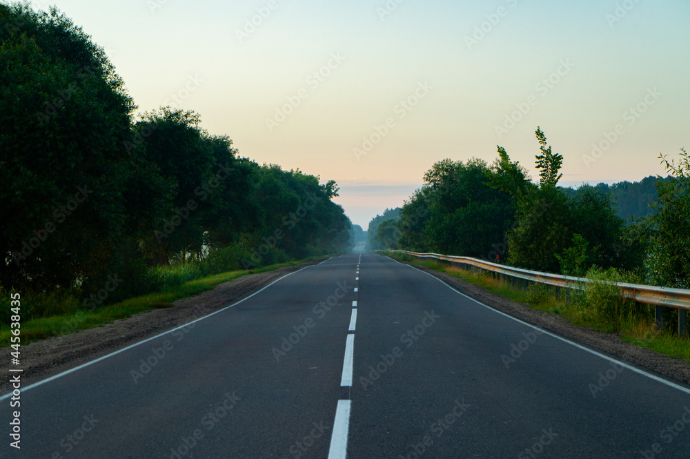 Calm empty asphalt road without cars at sunrise Calm empty asphalt road without cars at sunrise