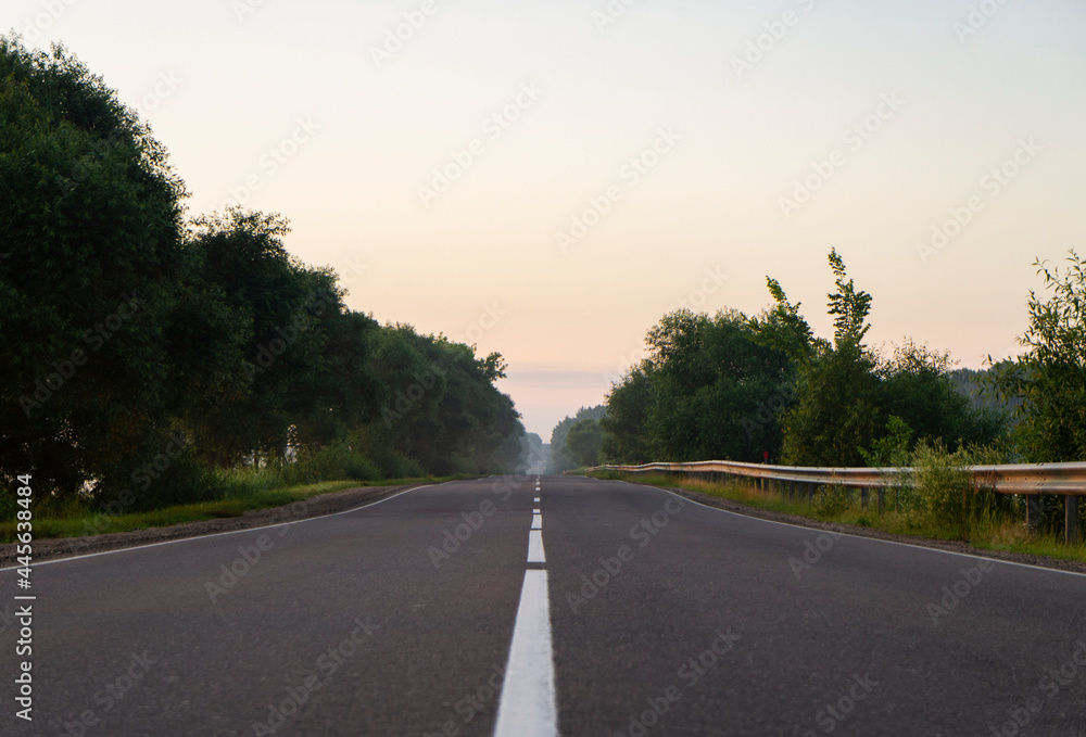 Calm empty asphalt road without cars at sunrise Calm empty asphalt road without cars at sunrise
