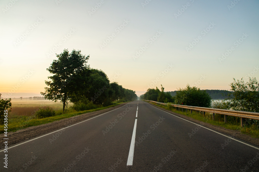 Calm empty asphalt road without cars at sunrise Calm empty asphalt road without cars at sunrise