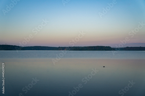Calm beautiful sunrise over the lake with sky reflection in water © Payllik