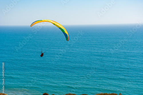 Paragliders with the beautiful blue open ocean, waves, and water behind them. Location near blacks beach, San Diego County, California.