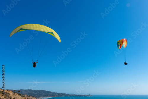 Paragliders with the beautiful blue open ocean, waves, and water behind them. Location near blacks beach, San Diego County, California.