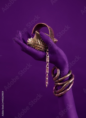 magenta woman's hand with gold jewelry. Oriental Bracelets on a black painted hand. photo