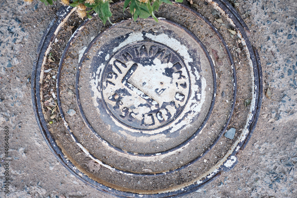 photo from the top of the manhole cover surrounded by asphalt, slightly painted with white paint