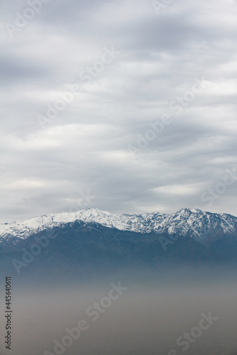 Mountain top covered in snow above the pollution clouds of urban area city in Santiago, Chile