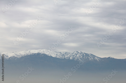Mountain top covered in snow above the pollution clouds of urban area in Santiago  Chile