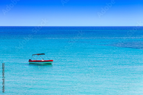 Lone boat in the Mediterranean Sea in the resort village of Protaras on the island of Cyprus. Landscape in the style of minimalism. © Photojulia