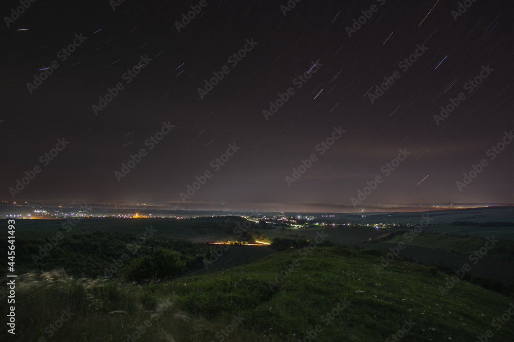 Starry sky over a field and a small town in summer in Ukraine