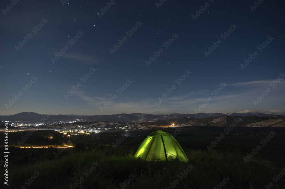 Night landscape, tent against the background of the starry sky and city lights on a hill in Ukraine