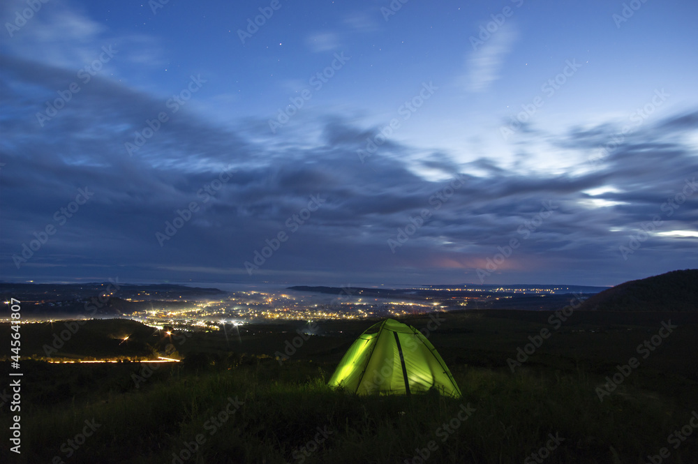 Obraz premium Morning landscape, tent against the background of sunrise and city lights on a hill in Ukraine