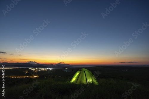 Morning landscape, tent against the backdrop of the sunset and city lights on a hill in Ukraine