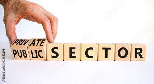 Private or public sector symbol. Businessman turns cubes and changes words 'public sector' to 'private sector'. Beautiful white background, copy space. Business, private or public sector concept.