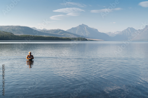 Blonde adult woman enjoys taking a dip in the cold waters of Lake McDonald in Glacier National Park during a heatwave © MelissaMN