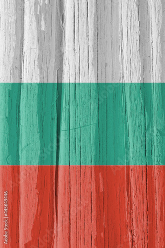 Fragment of the flag of Bulgaria on dry cracked wooden surface. It seems to flutter in the wind. Vertical background or backdrop with Bulgarian national symbol. Hard sunlight with shadows on old wood
