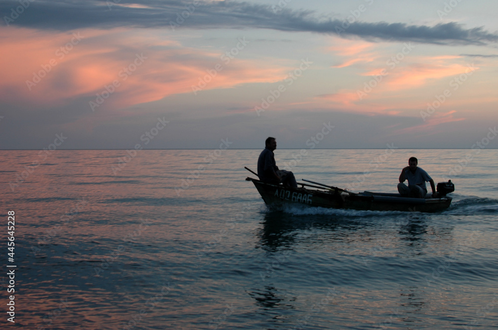 A boat with silhouettes of people at sunset. Seascape. Sunset on the sea.