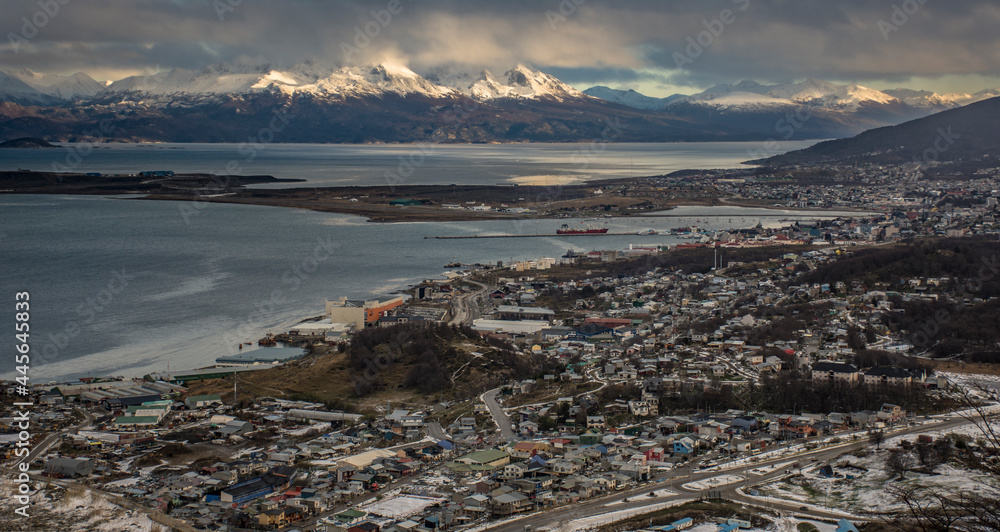 Panoramic shot of Ushuaia city at afternoon and Andes Mountains at the background with sunlight and clouds. Ushuaia, End of the World City, Tierra del Fuego province, Argentina. 