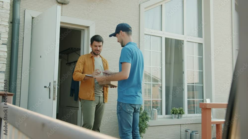 Delivery worker is bringing package to male customer's house giving box standing outside at front door. Occupation and postal service concept. Delivery worker is bringing package to male customer's house giving box standing outside at front door. Occupation and postal service concept.