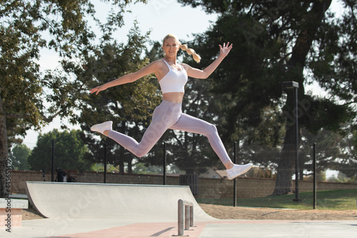 Healthy and fit atrractive blonde woman leaping to the right over obstacles at the park while looking ahead