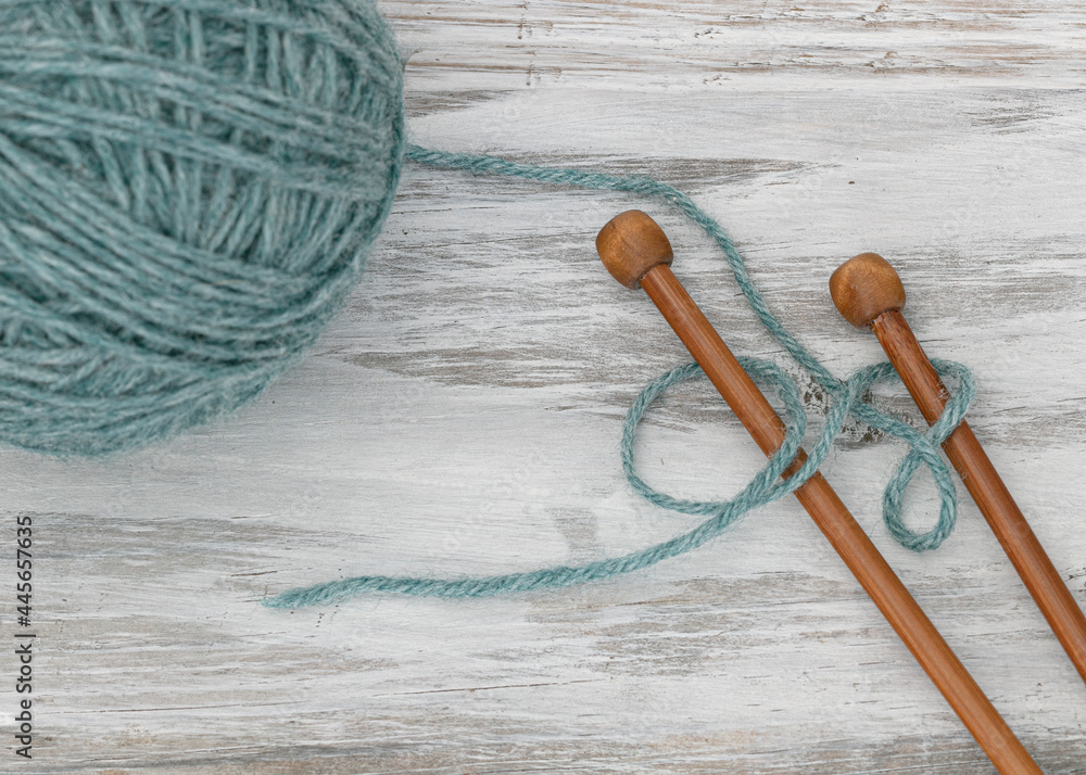 wood knitting needles and blue yarn on white  wood table 