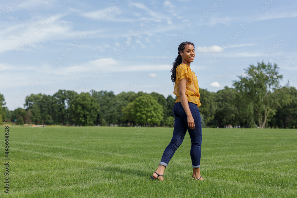 smiling African American woman walking outdoors on the grass at a park smiling African American woman walking outdoors on the grass at a park