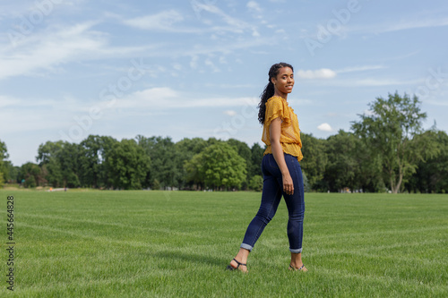 smiling African American woman walking outdoors on the grass at a park