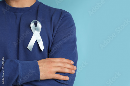 Closeup view of man with ribbon on light blue background, space for text. Urology cancer awareness
