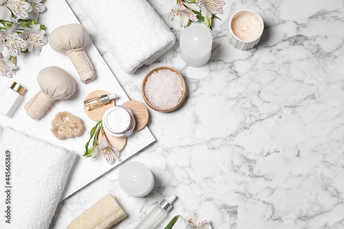 Flat lay composition with spa essentials on white marble background. Space for text