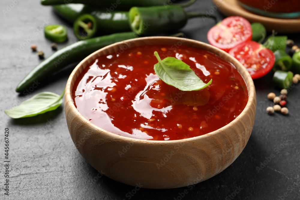 Spicy chili sauce with basil in bowl on black table, closeup Spicy chili sauce with basil in bowl on black table, closeup