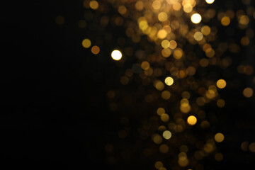 Blurred view of golden lights on black background. Bokeh effect