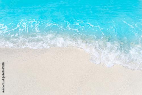 Sea wave and bubble on a sandy white beach blue sea background texture and copy space holiday concept