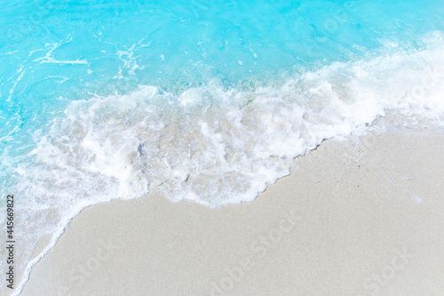 Sea wave and bubble on a sandy white beach blue sea background texture and copy space holiday concept