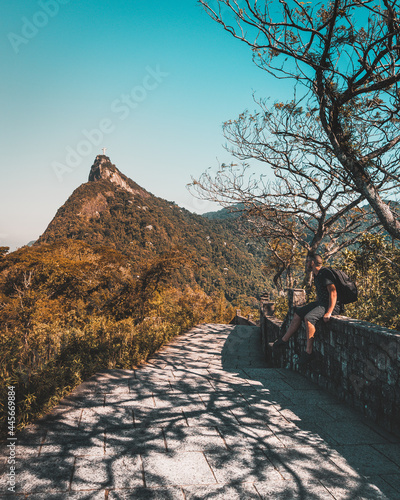 Tourist sitting on a wall near a trail of Mirante Dona Marta and looking at Corcovado Mountain photo