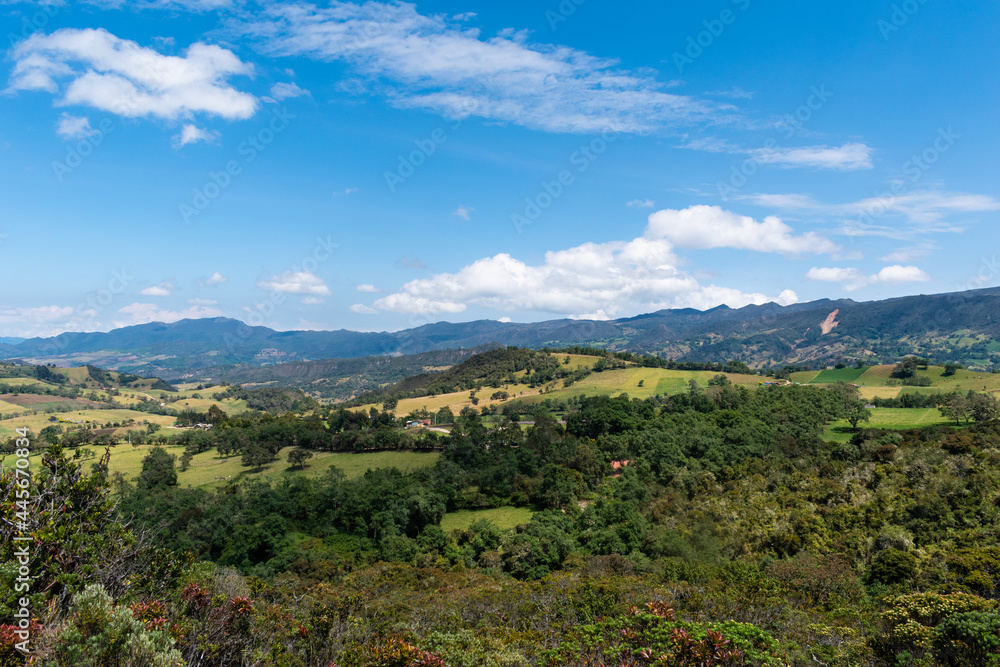 Landscape of mountains, country houses and crops with a blue sky and some clouds in Colombia.