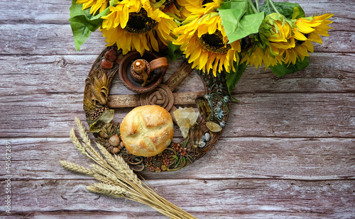 Wiccan Altar for Lammas, Lughnasadh pagan holiday. wheel of the year with ears of wheat, homemade bread, flowers, minerals, candle on dark background. symbol of celtic wiccan sabbath, summer season.  photo