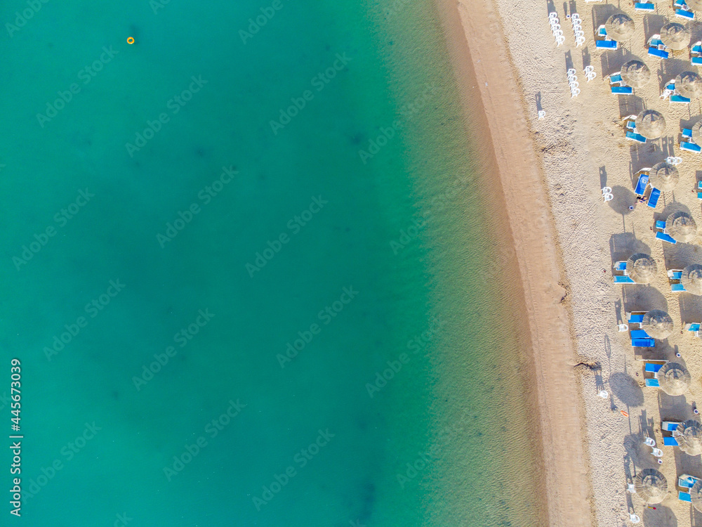 Aerial view of sandy beach with colorful umbrellas, swimming people in sea bay with transparent blue water at sunset in summer. Travel in Egypt. Top view.