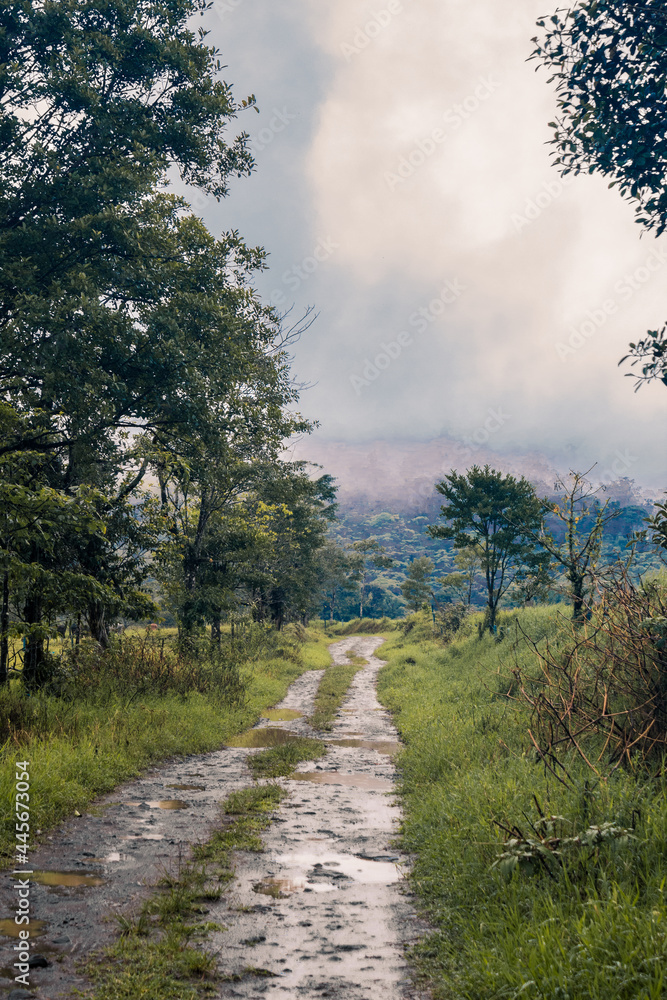 rural dirt road in rainy season through rural farms near the tropical cloud forest filled mountains of Costa Rica rural dirt road in rainy season through rural farms near the tropical cloud forest filled mountains of Costa Rica