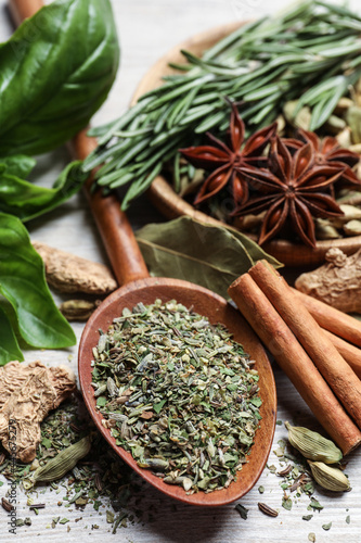 Different natural spices and herbs on wooden table, closeup