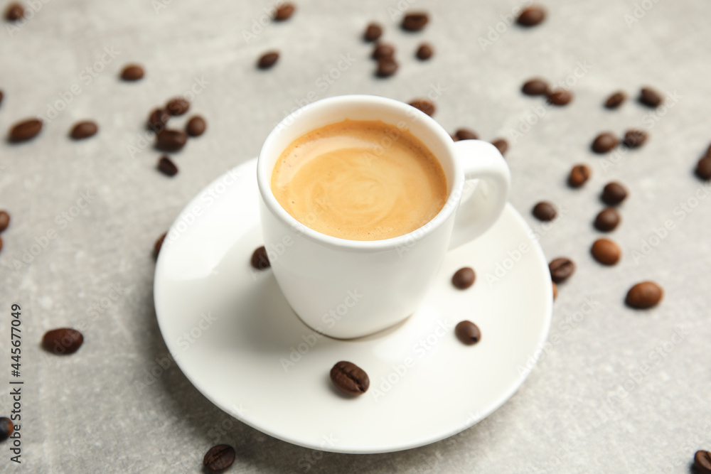 Cup of hot aromatic espresso and roasted beans on light table Cup of hot aromatic espresso and roasted beans on light table