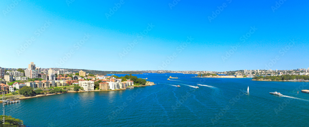 Ships driving on clear water; tall buildings on both sides of a river. Panorama
