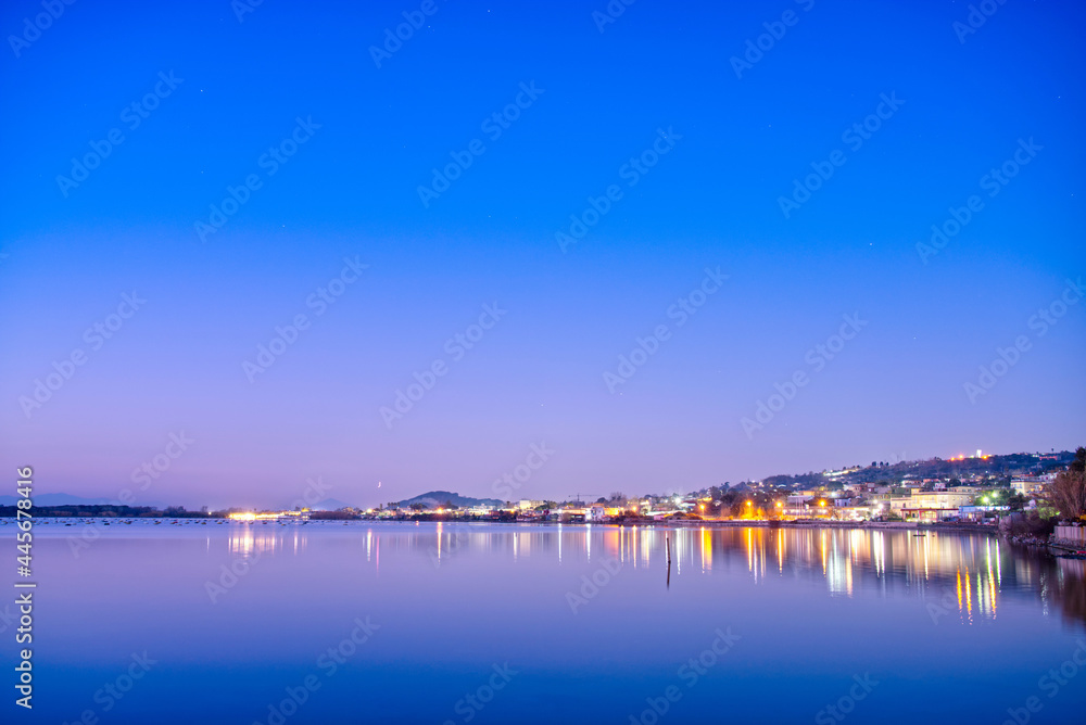 Night view of Lake Fusaro in Naples, Italy, with blue sky and water