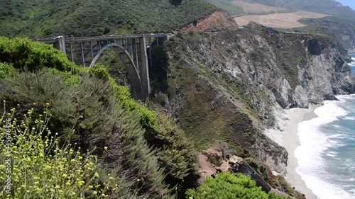 View of Bixby Creek Bridge in Big Sur State Park in California. Vegetation and ocean waves can be seen along the coastline on Highway 1.