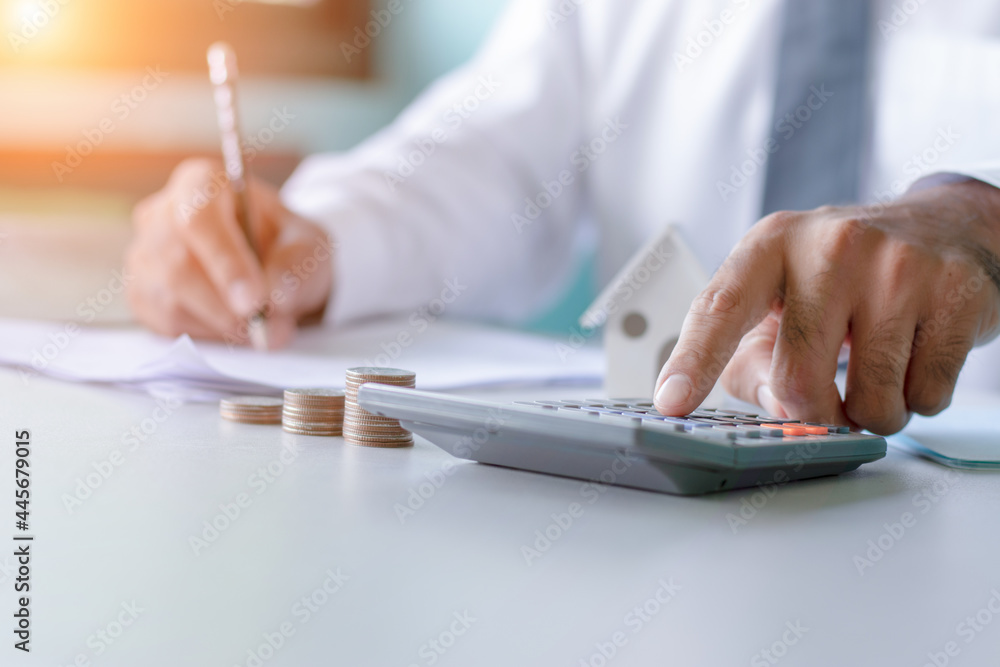 Close-up of a man in white using a calculator and taking notes accounting report concept of costing and saving money for building a solid foundation in the future.