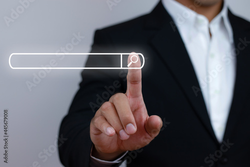 A business man with his index finger presses the search button on the toolbar to find useful information.