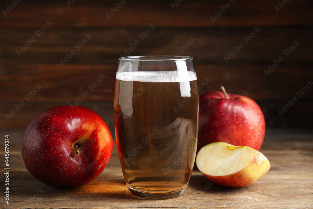 Glass of delicious cider and ripe red apples on wooden table Glass of delicious cider and ripe red apples on wooden table