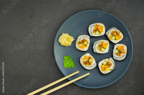 Close up of delicious Japanese sushi in a blue plate in a black background and a pair of chopsticks, top view